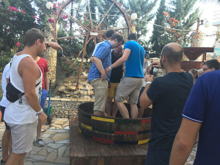 men crushing grapes by stepping barefoot on the grapes inside wood vat at Zahaios winery
